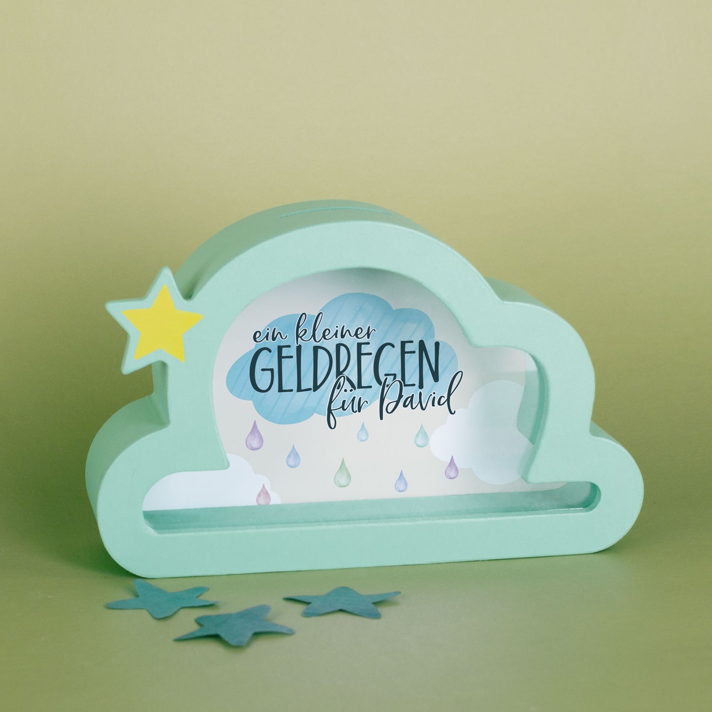 Spardose in Wolkenform mit gelbem Stern und Spruch "ein kleiner Geldregen für David" auf grünem Hintergrund.