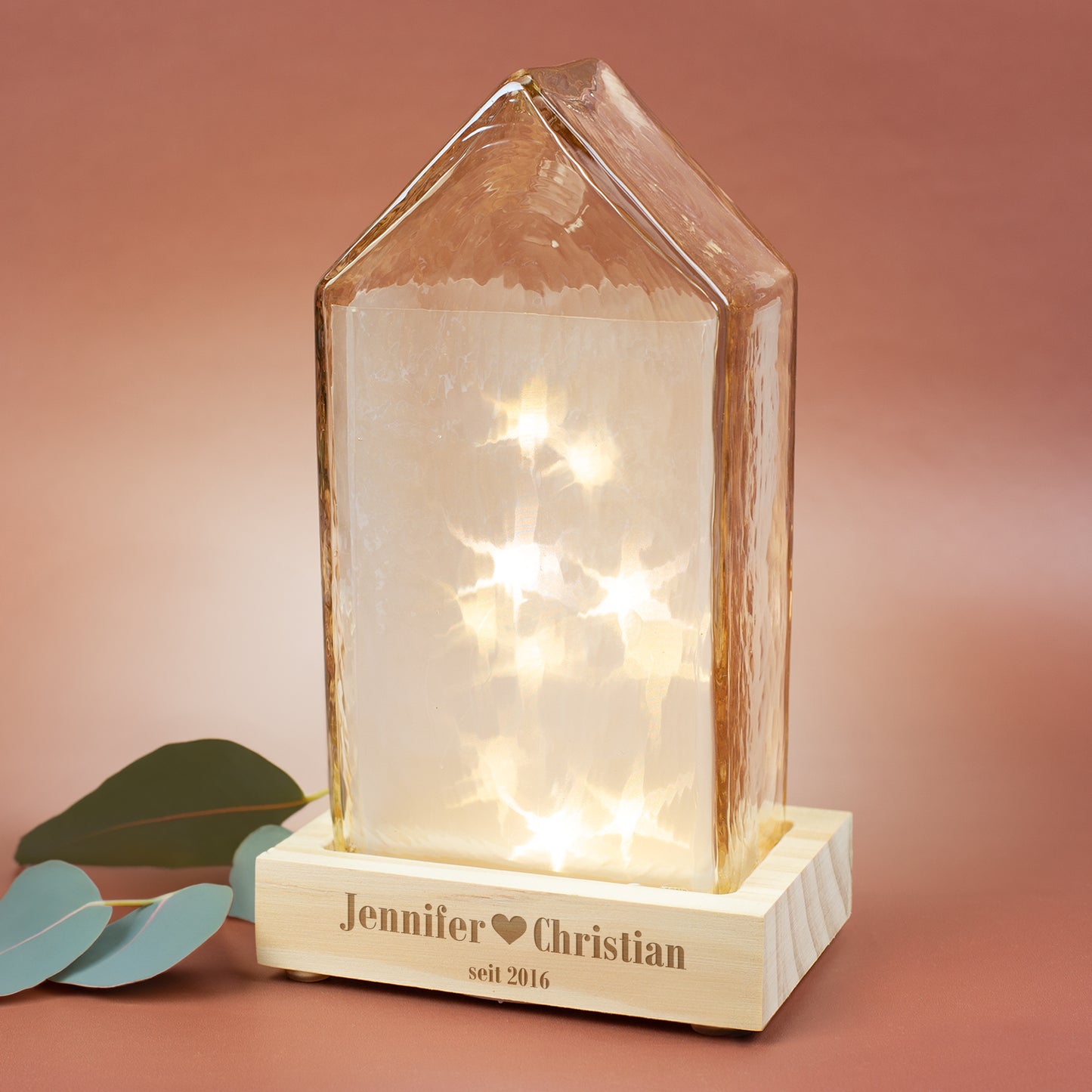 LED-Glashaus von Leonardo mit Gravur „Jennifer - Christian“ auf Holzfuß, warmweiße Sternbeleuchtung innen.