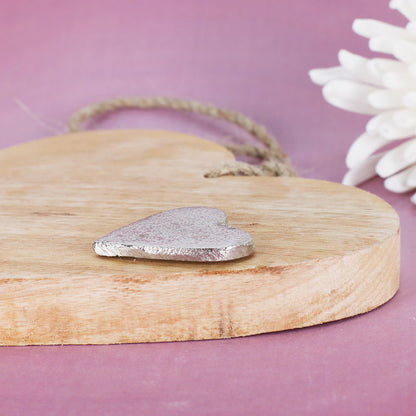 Detailansicht vom Holzherz mit silberfarbenem Metallherz und natürlicher Holzstruktur