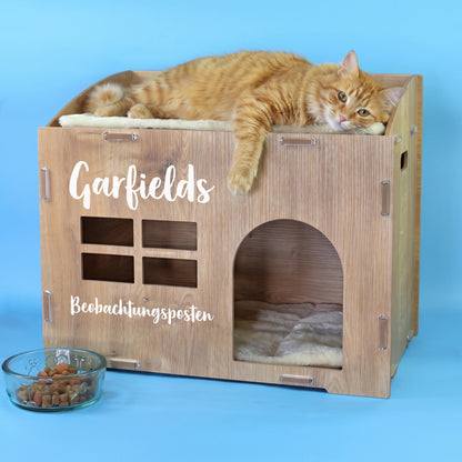 Katzenhaus in Eiche-Optik mit personalisiertem Namen Garfields, Wunschtext Beobachtungsposten und roter Katze auf der Liegefläche