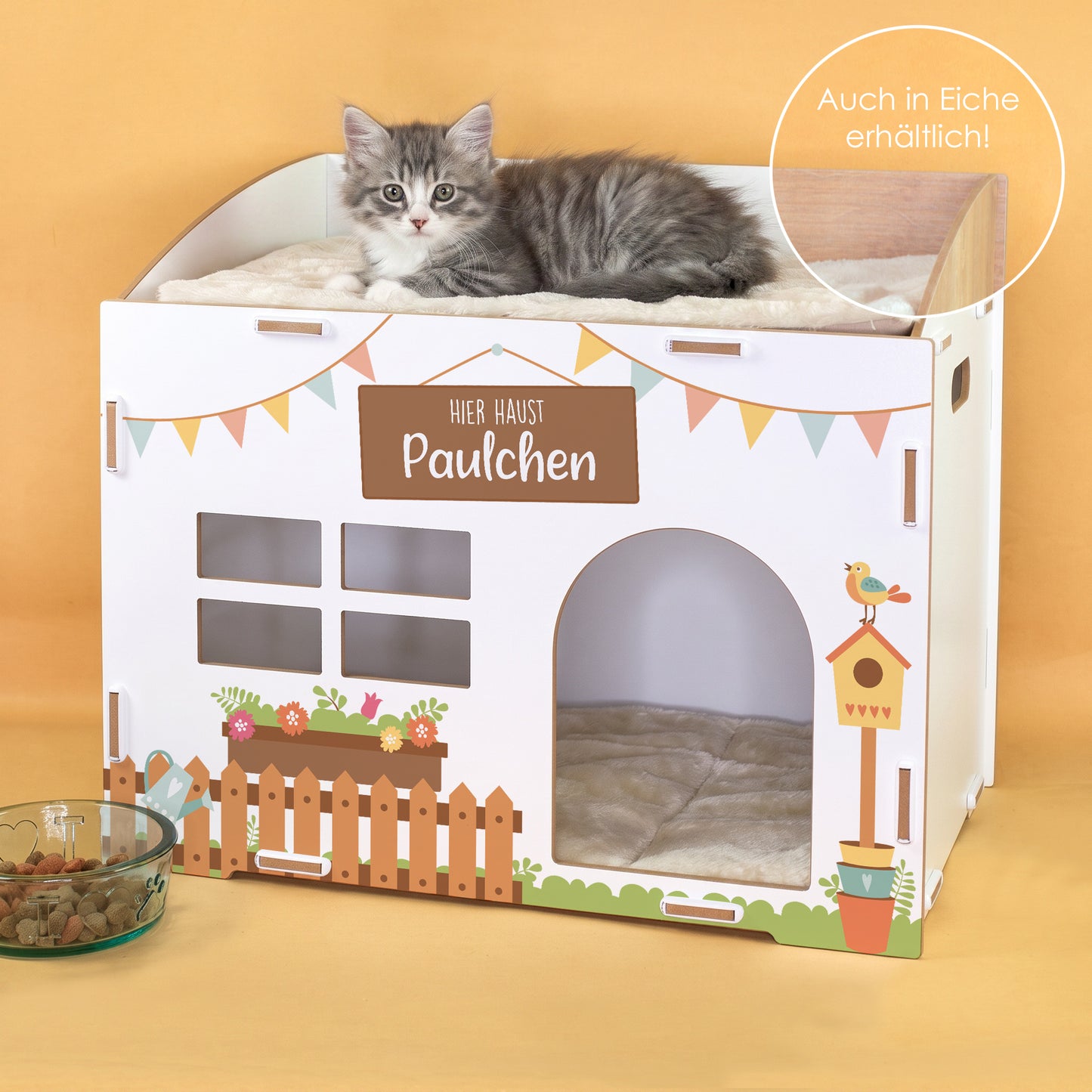 Weißes Katzenhaus aus Holz mit Wunschtext Hier haust Paulchen, Kuschelkissen und grauer Katze
