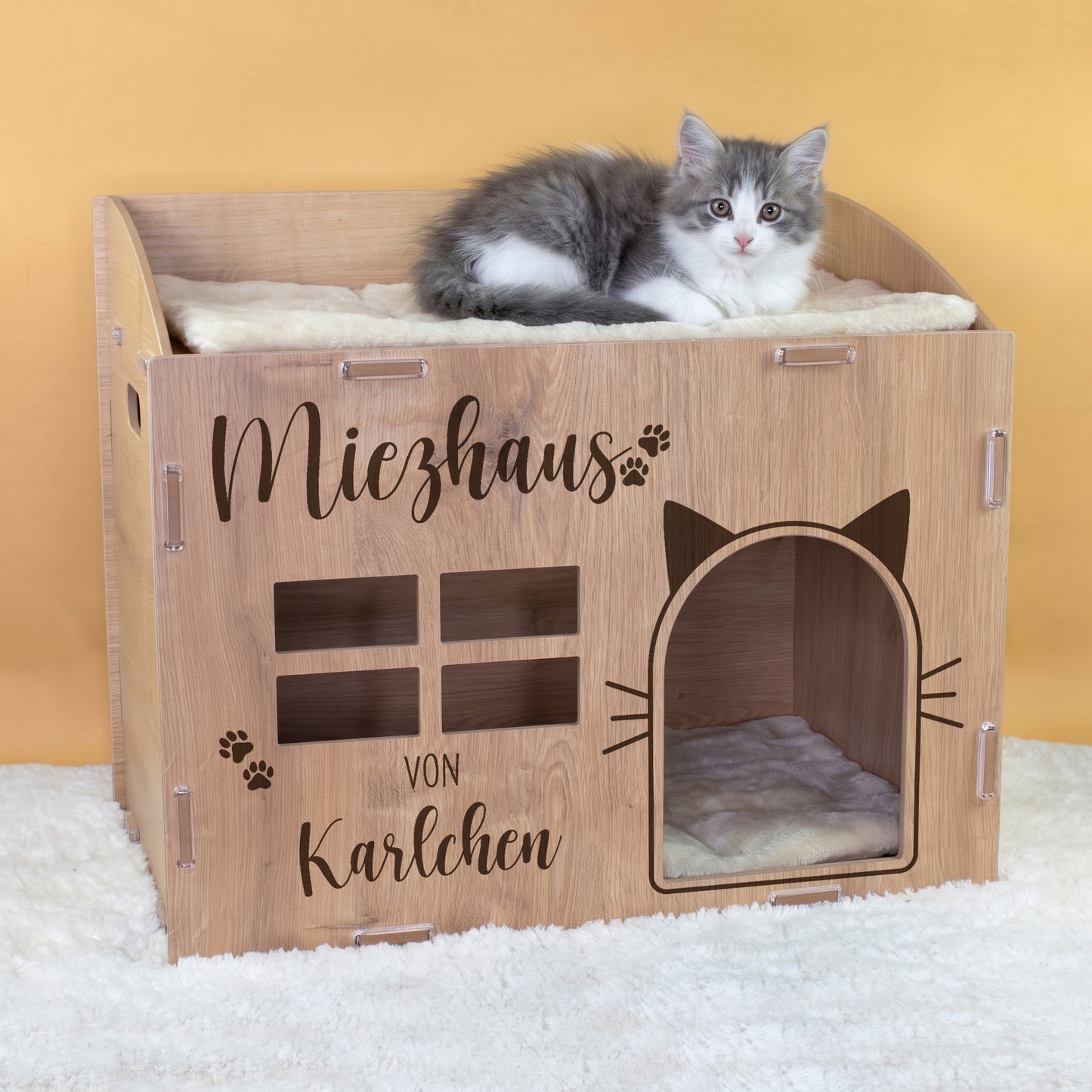 Personalisiertes Katzenhaus aus Holz in Eiche mit Miezhaus-Aufdruck und Name Karlchen, Katze liegt auf der oberen Liegefläche