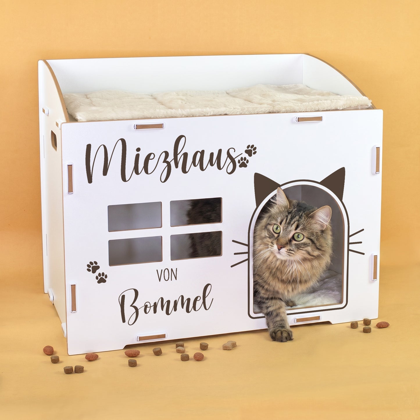 Weißes Katzenhaus mit Miezhaus-Aufdruck und Name Bommel, Katze schaut aus der Katzenöffnung