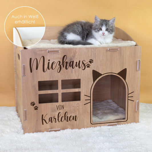 Katzenhaus aus Holz mit Katze auf der Liegefläche und Hinweis auch in Weiß erhältlich