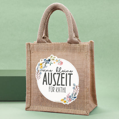 Personalisierte Geschenktasche aus Jute "eine kleine Auszeit" von der Seite vor grünem Hintergrunf