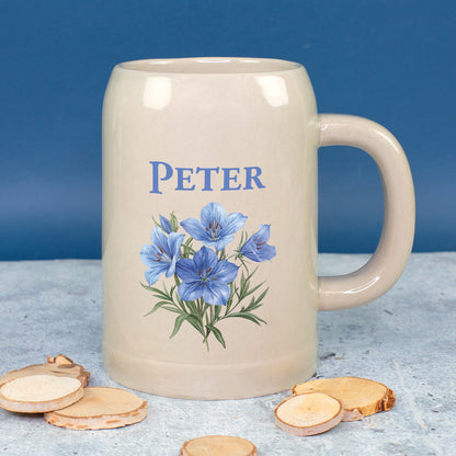 Personalisierter Bierkrug mit Namen Peter und Enzianblumen auf blauem Hintergrund