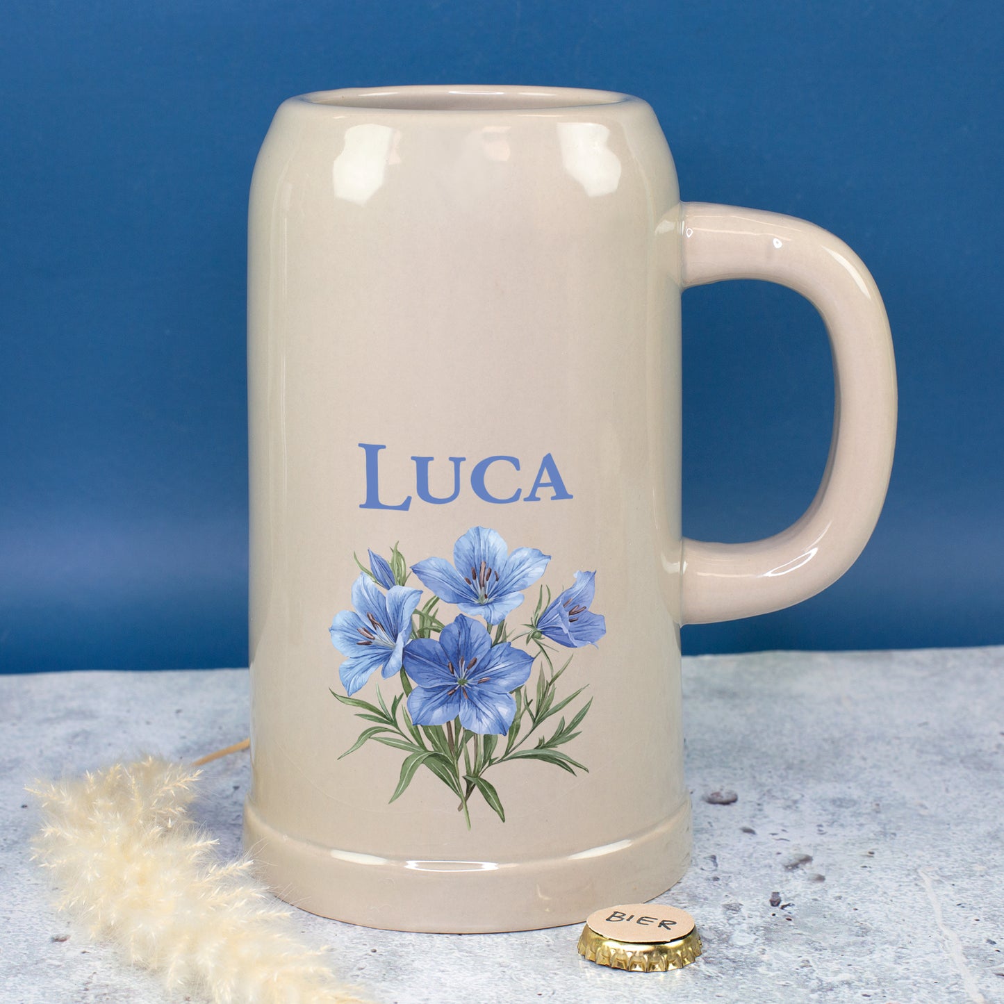 Personalisierter Bierkrug mit Namen Luca und Enzianblumen auf blauem Hintergrund