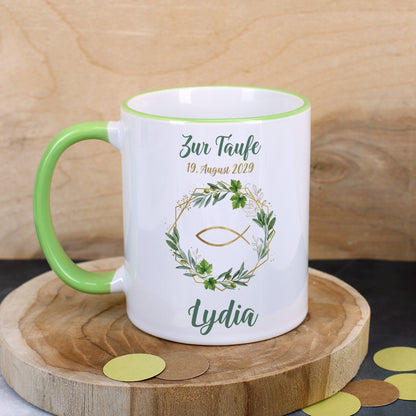 Religiöse Keramiktasse zur Taufe mit Ichthys-Fisch im Oliven-, Weinkranz, personalisiert mit Name „Lydia“ und Datum, dekorativ inszeniert