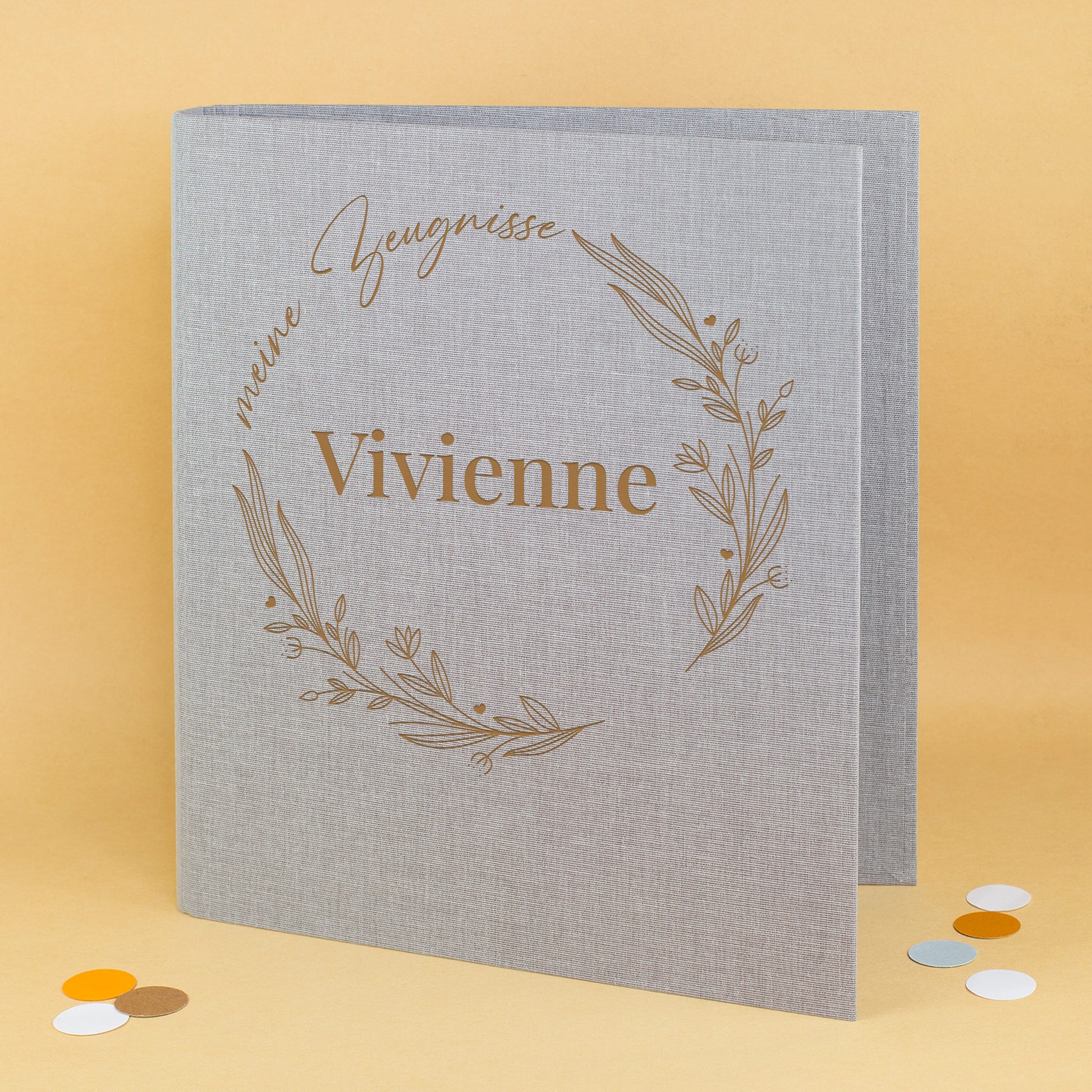 Graue Zeugnismappe aus Leinen mit floralen Elementen im Ring, Aufdruck „meine Zeugnisse“ und Name „Vivienne“.