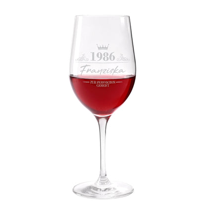 Leonardo Weinglas mit Gravur „1986 Franziska – Zur Perfektion gereift“, mit Rotwein gefüllt auf hellem Hintergrund