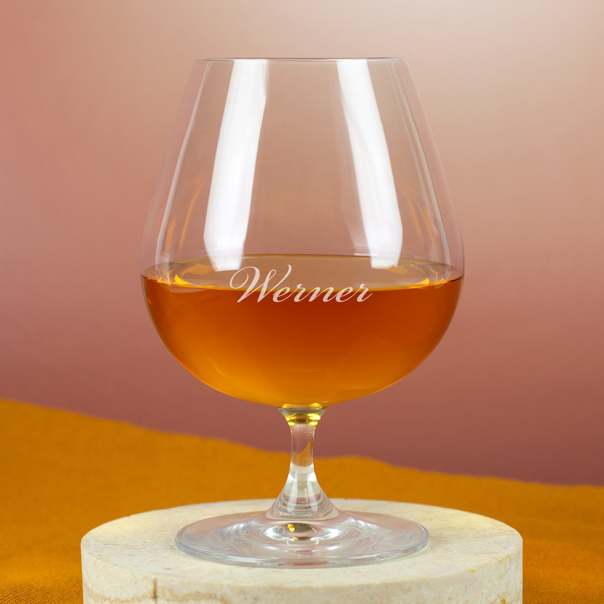 Leonardo Cognacschwenker mit Gravur „Werner“ – gefüllt mit goldbraunem Cognac, auf hellem Steinuntergrund.