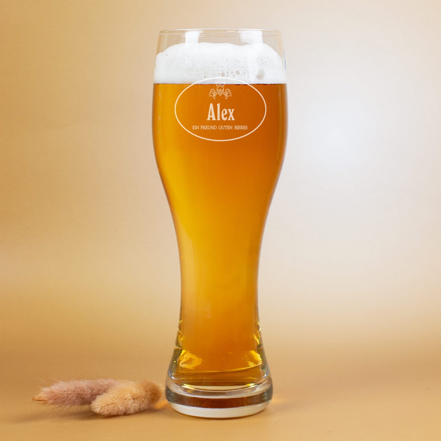 Ein graviertes Weizenglas mit Namen Alex, gefüllt mit Bier, auf hellem Hintergrund