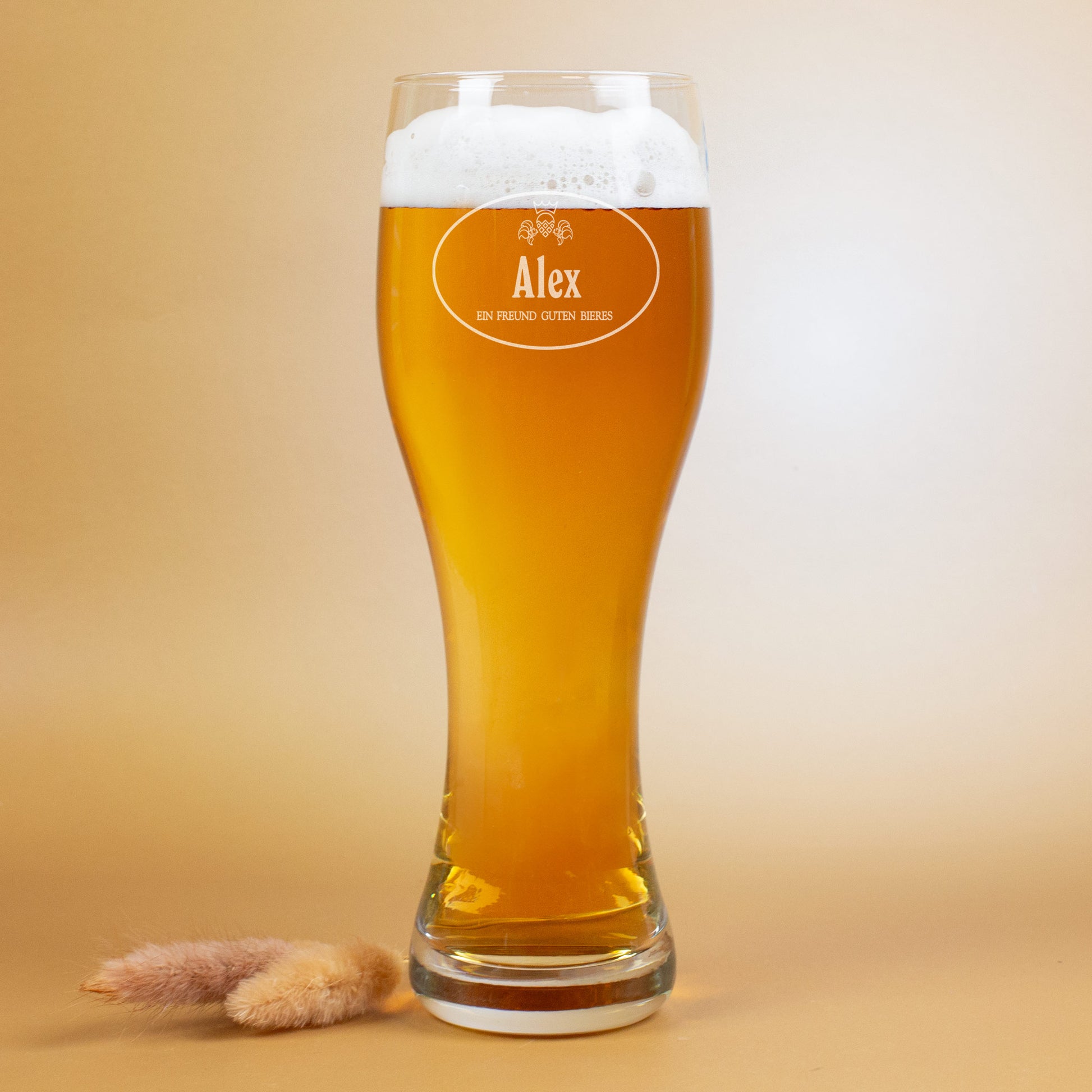 Ein graviertes Weizenglas mit Namen Alex, gefüllt mit Bier, auf hellem Hintergrund