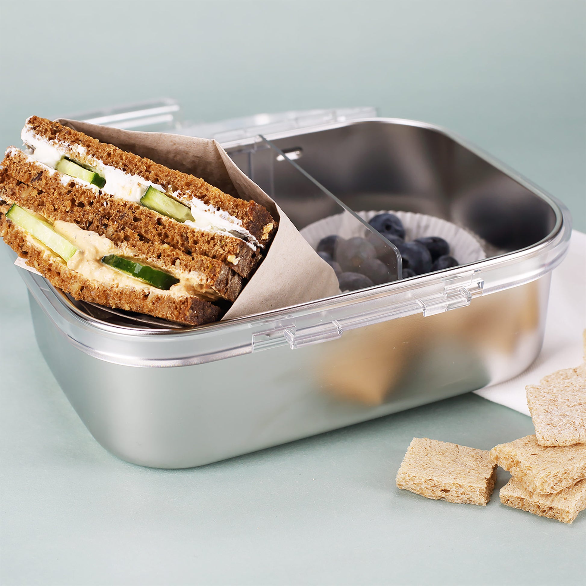 Geöffnete Brotdose mit belegtem Sandwich, Trennwand und Heidelbeeren