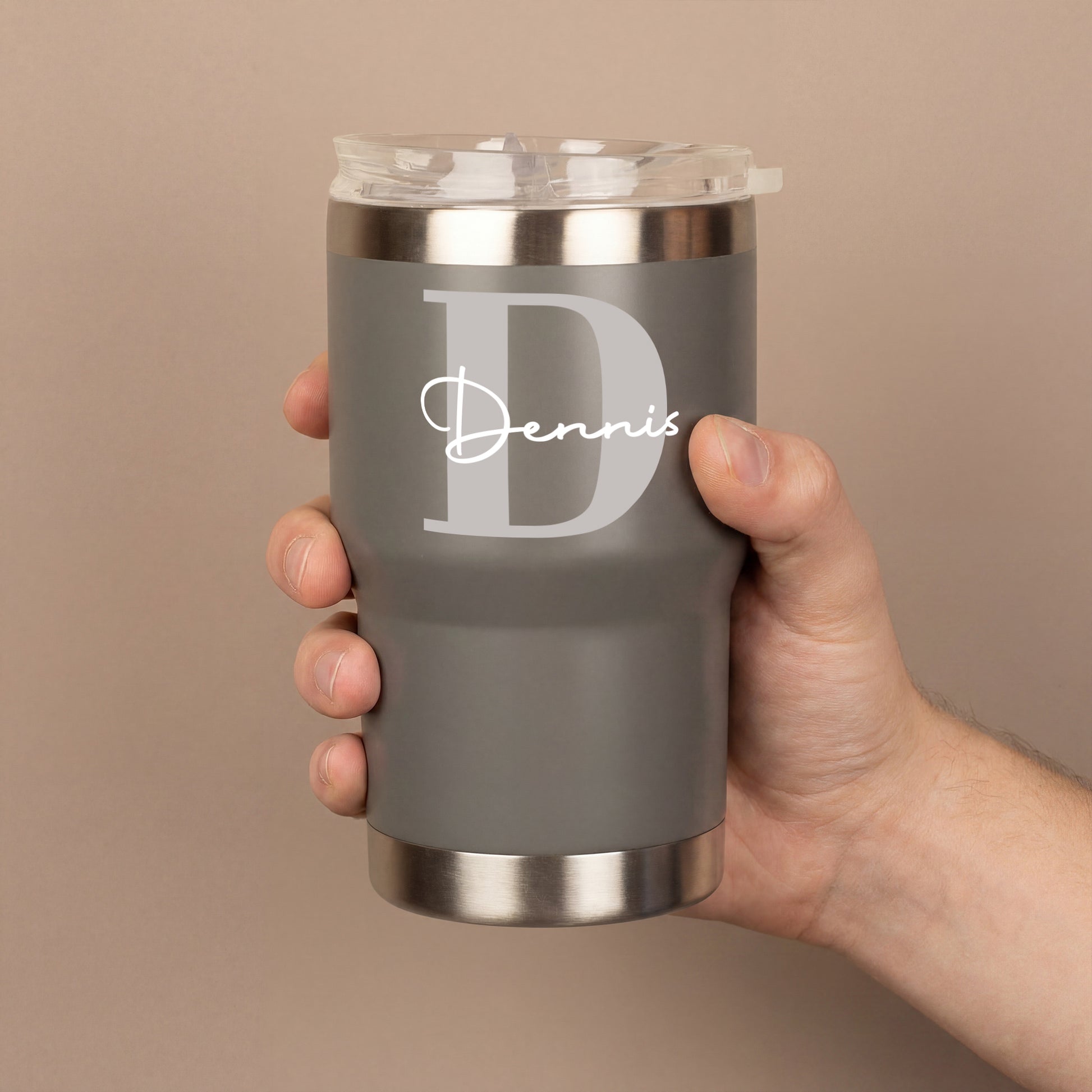 Grauer personalisierter Thermobecher mit großer Initiale D und Name Dennis in einer Hand gehalten