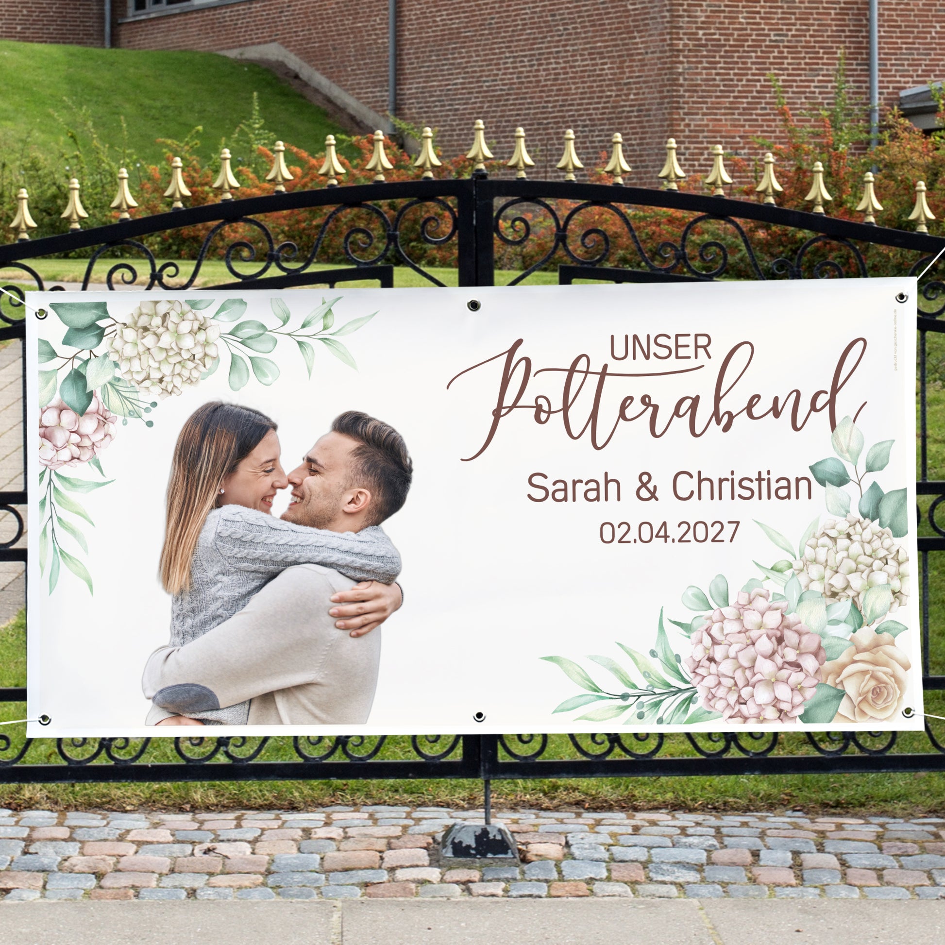 Großes Polterabend-Banner mit Foto, Namen Sarah und Christian und Blumenmotiv an einem Gartentor