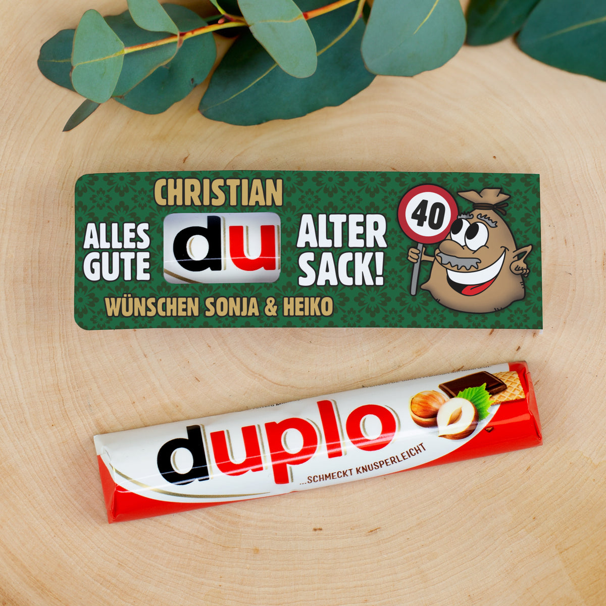 duplo Schokoriegel mit personalisierter Geburtstagsbanderole dekorativ auf Holzuntergrund
