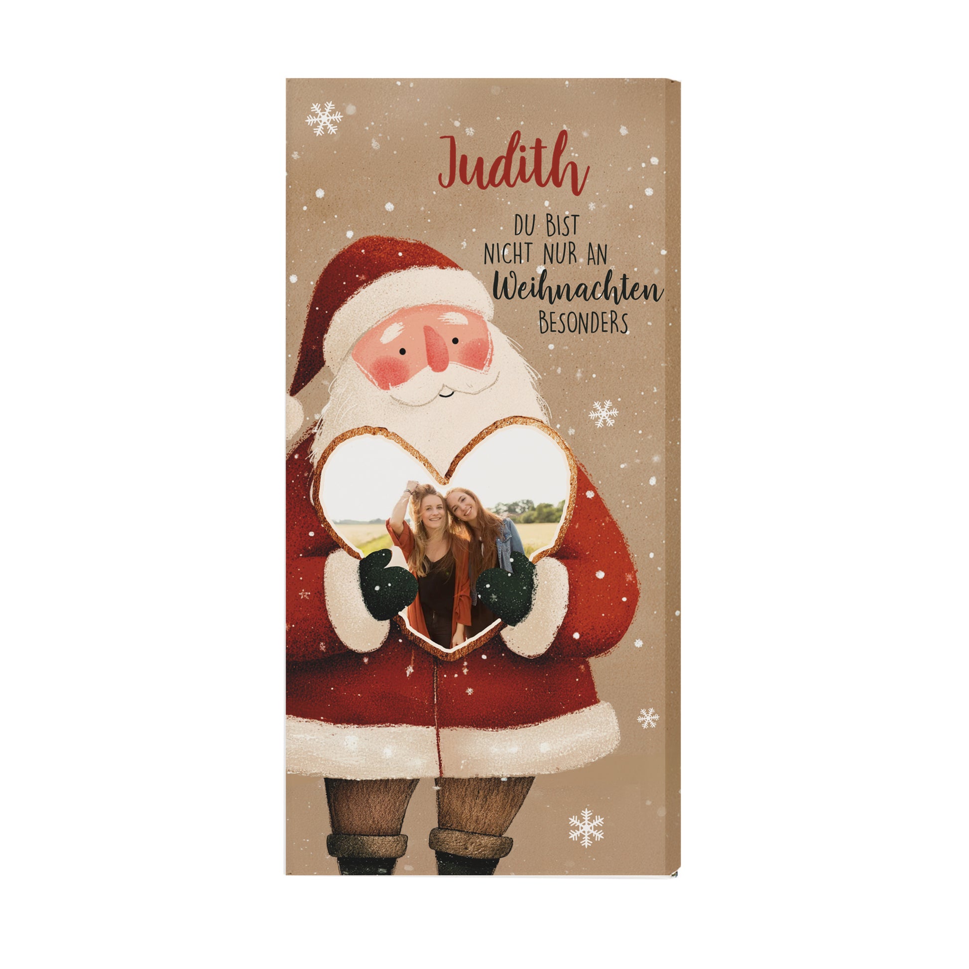 Weihnachts-Schokolade mit Herzfoto und Namensdruck. Die Verpackung zeigt einen Weihnachtsmann mit rotem Mantel, weißen Schneeflocken und dem Namen „Judith“. Das Foto ist in das Herz integriert. Die naturbraune Farbgebung der Verpackung sorgt für einen modernen und warmen Look – perfekte Geschenkidee für die Feiertage.