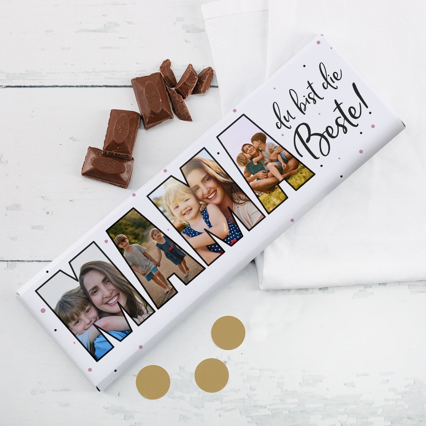 Personalisierbare Fotogeschenk-Schokolade für Mama mit 4 Bildern im Schriftzug „MAMA“ und aufgebrochener Schokolade auf weißem Tisch