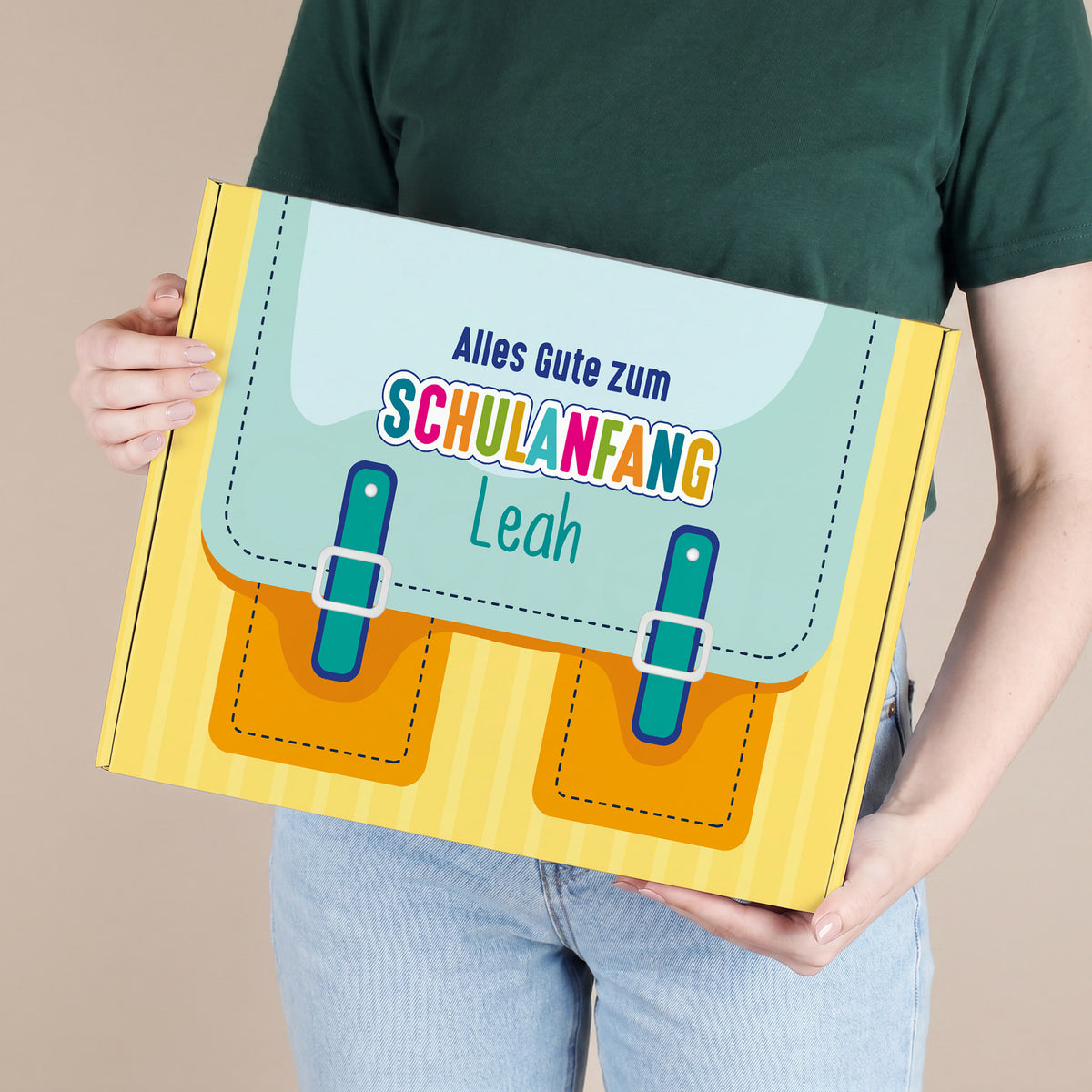 Große gelbe Geschenkverpackung zum Schulanfang mit Wunschname, von einer Person gehalten