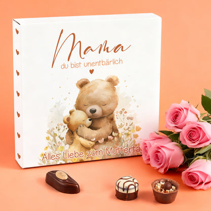 Muttertags Pralinenbox mit Bärenmotiv und Schriftzug „Mama du bist unentbärlich“ neben Rosen dekoriert