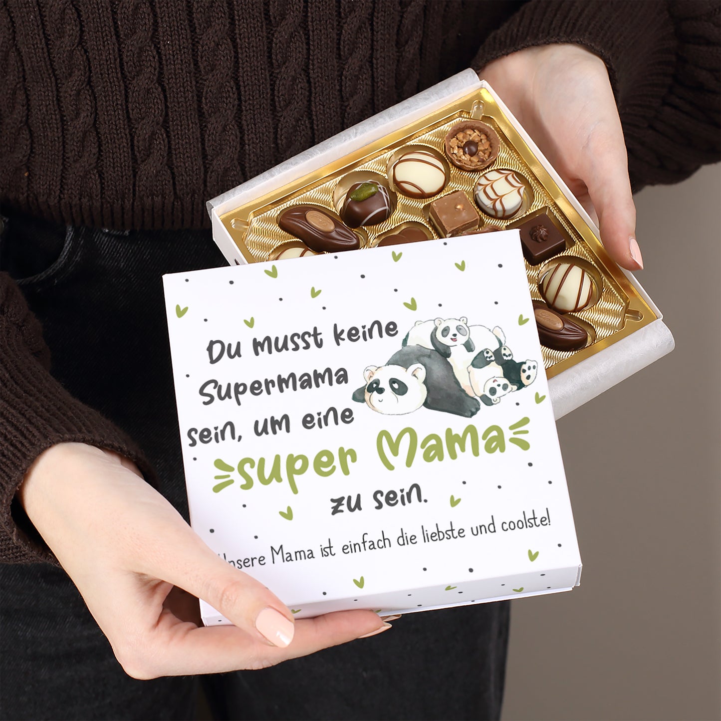 Geschlossene Geschenkbox Super Mama Panda mit Pralinen dekoriert und rosa Rosen daneben
