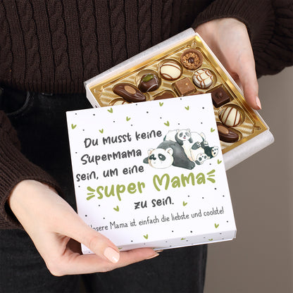 Geschlossene Geschenkbox Super Mama Panda mit Pralinen dekoriert und rosa Rosen daneben