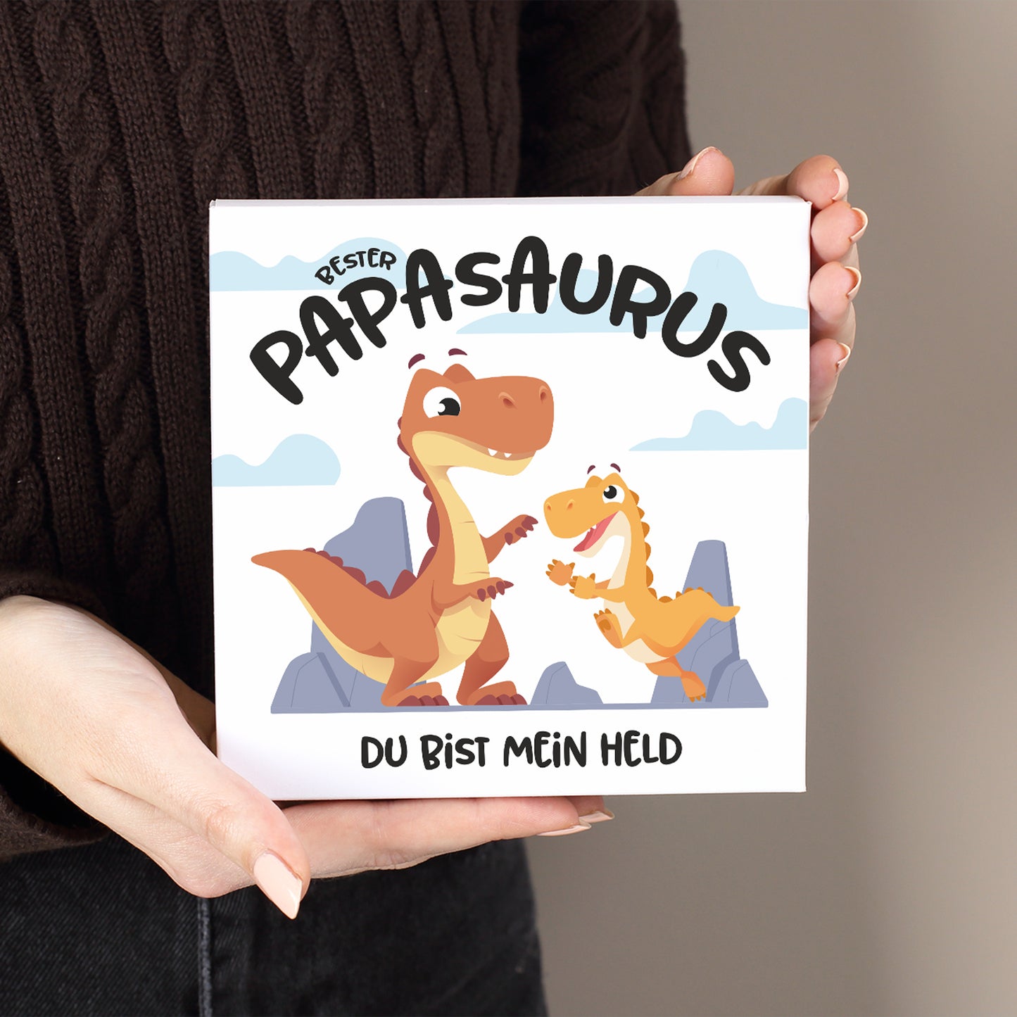 Weiße Pralinenschachtel mit Dino Motiv „Bester Papasaurus“ und individuellem Text in der Hand gehalten