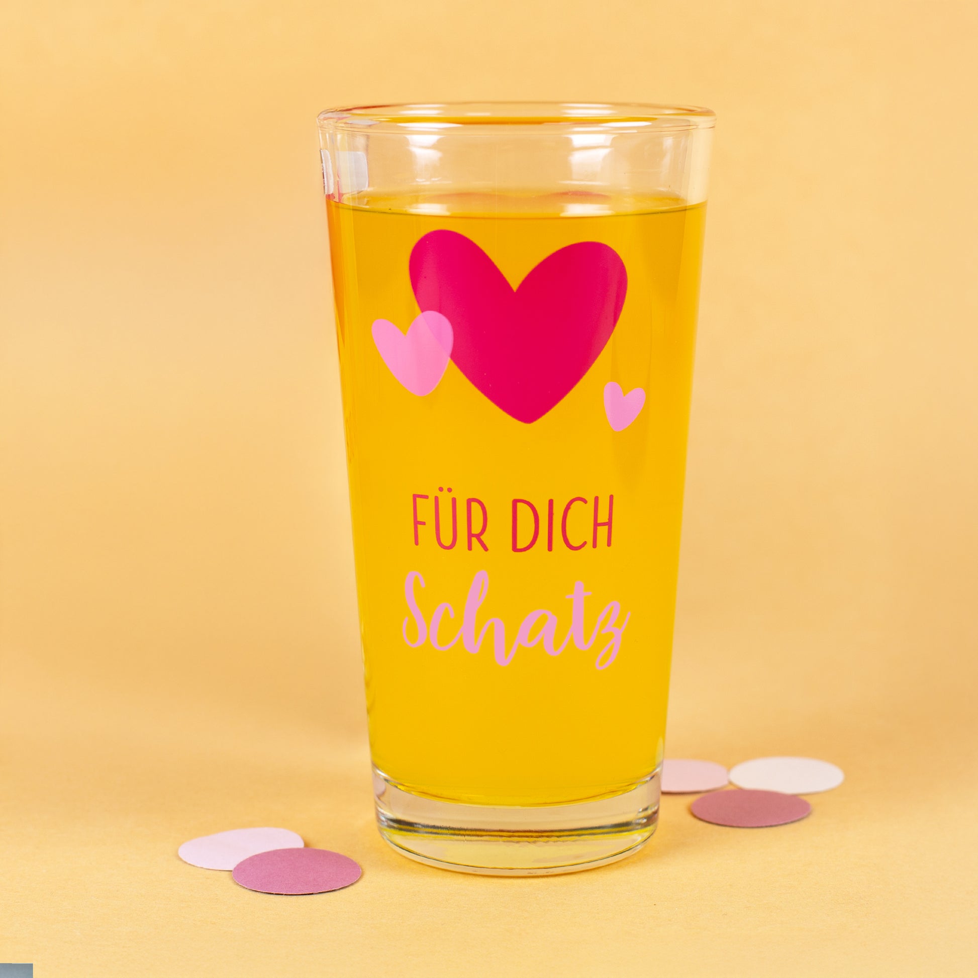 Personalisierbares Trinkglas mit Herz-Motiv und Schriftzug „Für dich Schatz“ auf gelbem Hintergrund