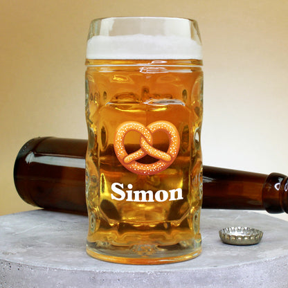 0,5-Liter-Bierglas mit Brezel-Motiv und Name Simon, auf Betonplatte mit Bierflasche und Kronkorken