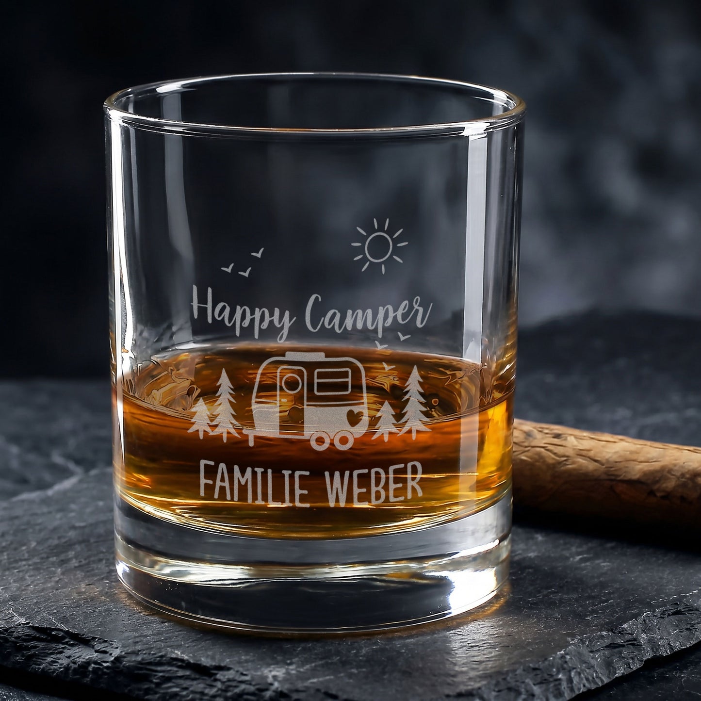 Whiskeyglas mit Camping-Gravur Happy Camper und Wunschtext Familie Weber auf dunklem Untergrund