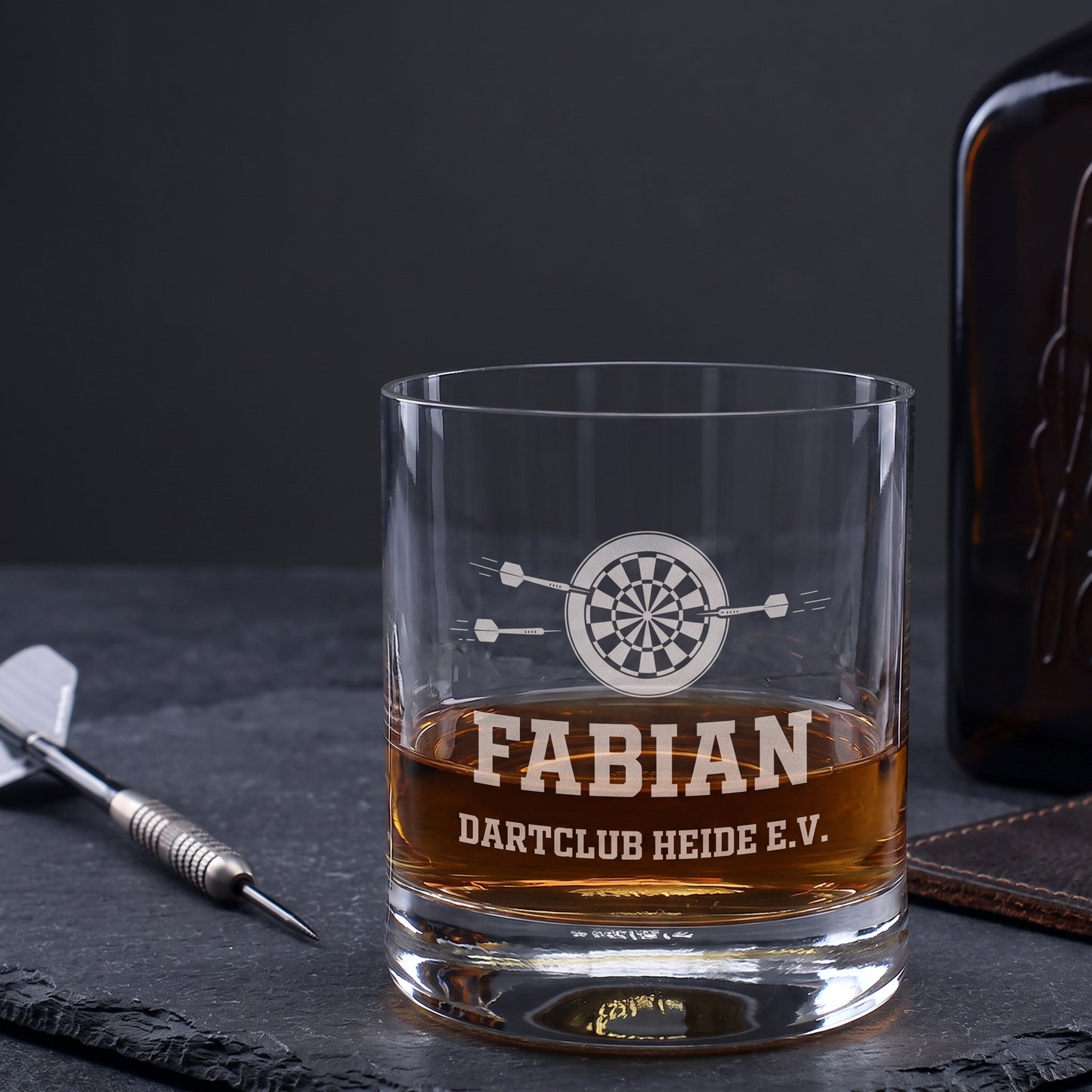 Personalisiertes Whiskyglas mit Dartscheibe, Name Fabian und Wunschtext Dartclub Heide e.V. neben Dartpfeil