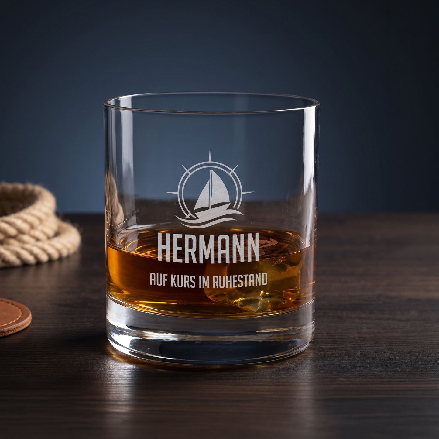 Personalisiertes Whiskeyglas für Segler mit Name Hermann und Wunschtext Auf Kurs im Ruhestand auf dunklem Holztisch