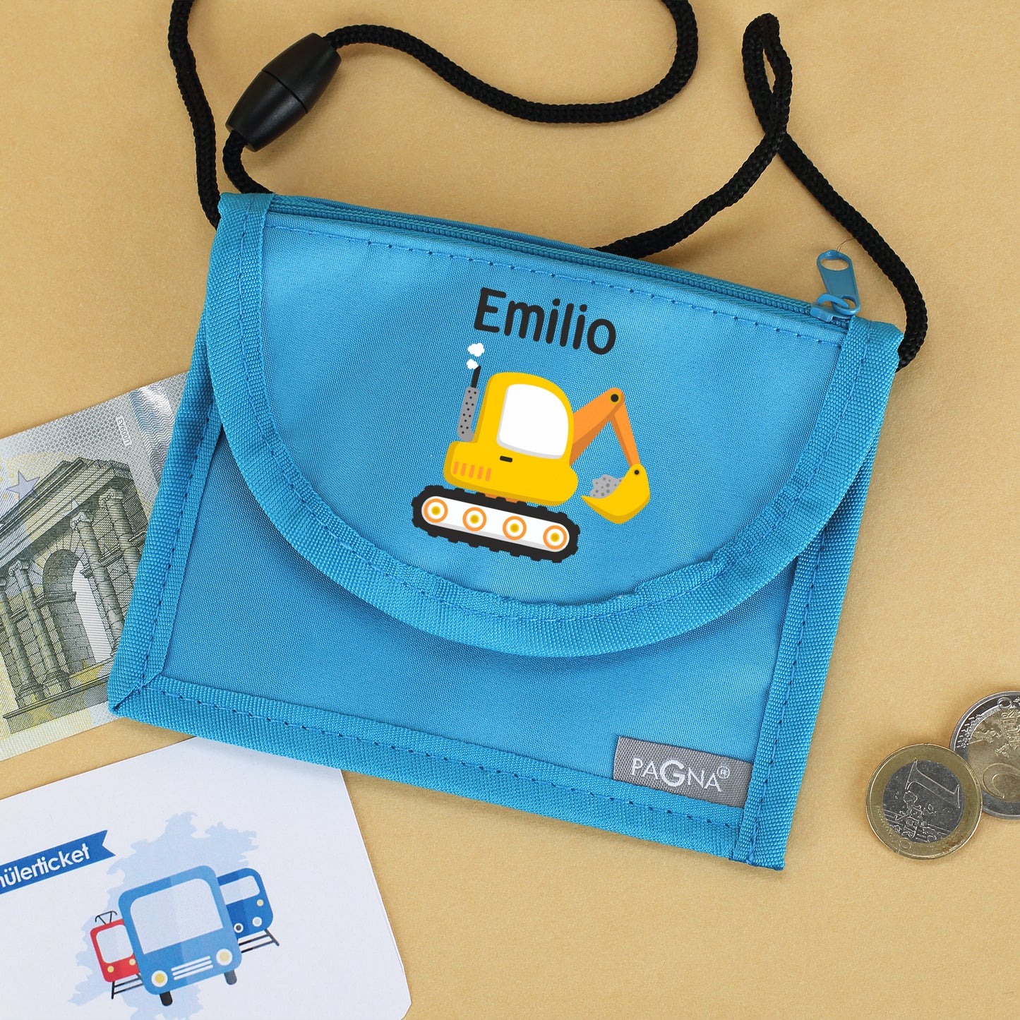 Blauer Brustbeutel mit Name Emilio und Bagger-Motiv neben Geld und Schülerticket