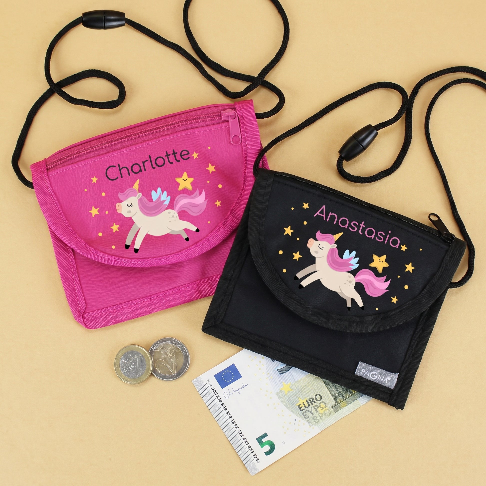 Pinker und schwarzer Brustbeutel mit personalisiertem Namen und Einhorn-Motiv, daneben Münzen und Geldschein als Beispiel für den Einsatz in Kindergarten und Schule.