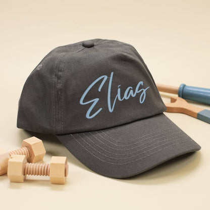 Dunkelgraues Basecap für Kinder mit Name in hellblau bestickt