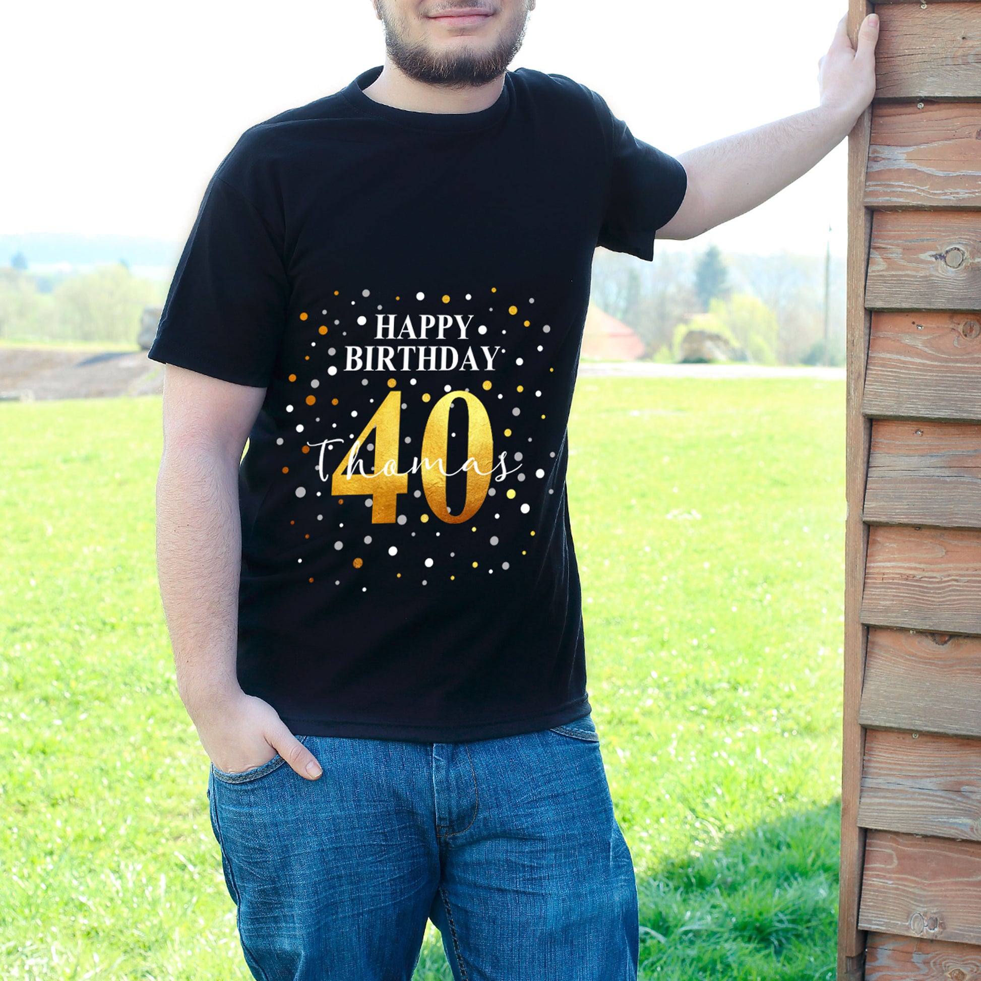 Mann mit „Happy Birthday 40“ T-Shirt und Name Thomas, draußen vor Holzhaus