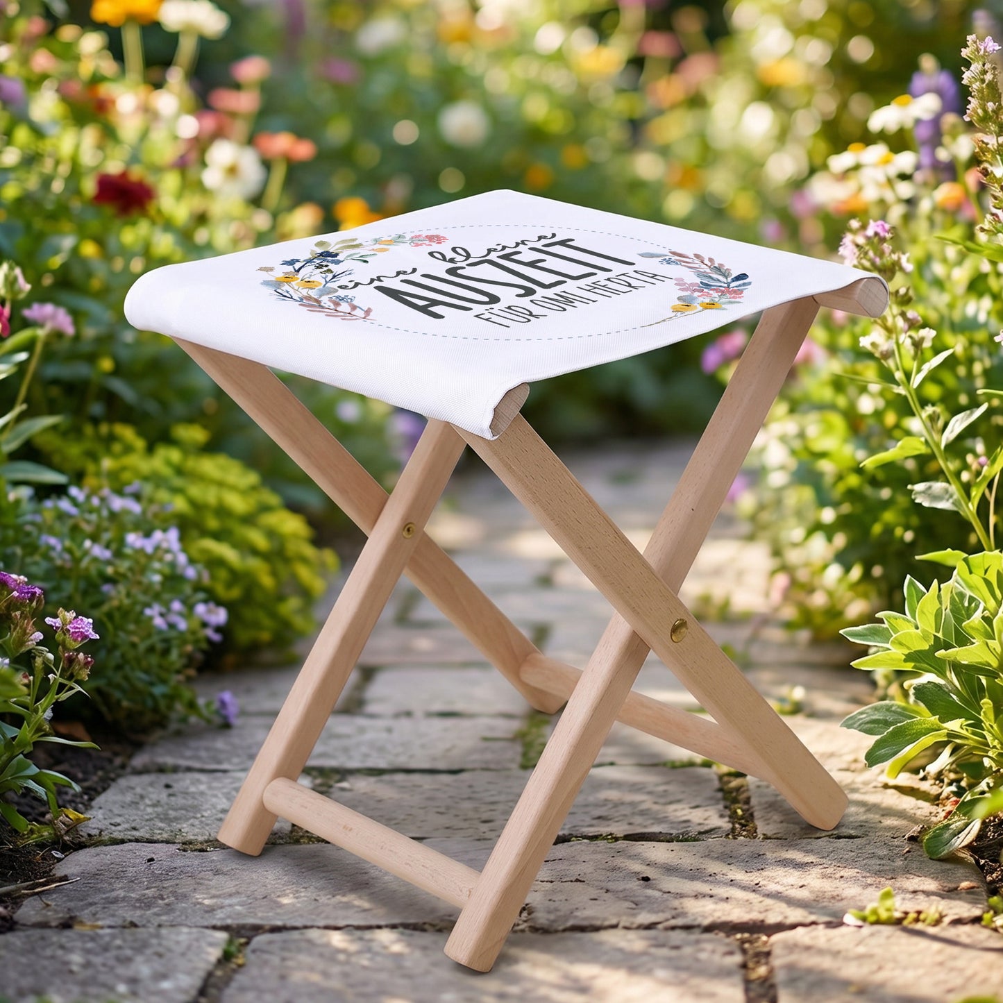 Personalisierter Klapphocker im Garten mit floraler Sitzfläche und Wunschtext