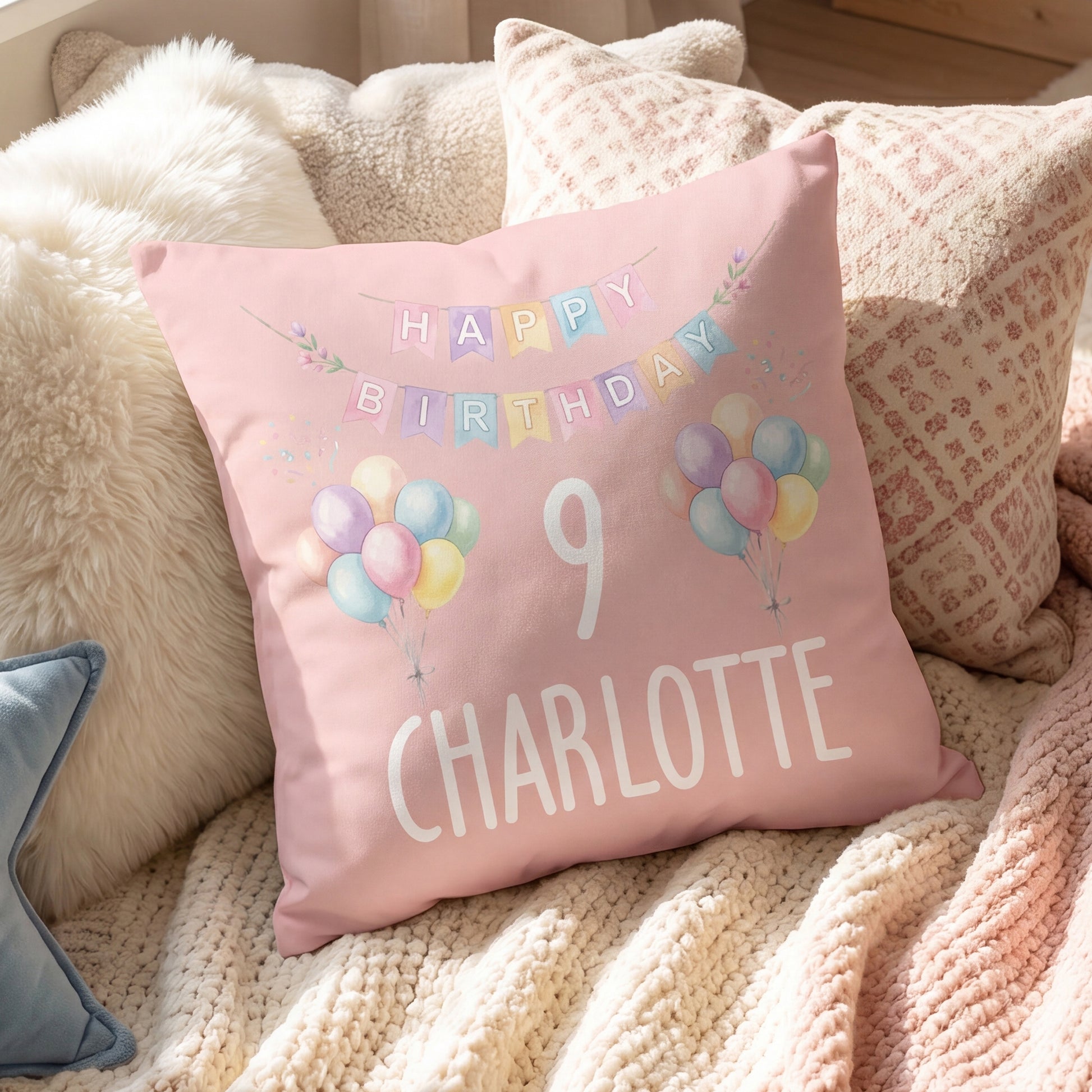 Rosa personalisiertes Geburtstagskissen mit Ballons, Zahl 9 und Name Charlotte auf dem Sofa
