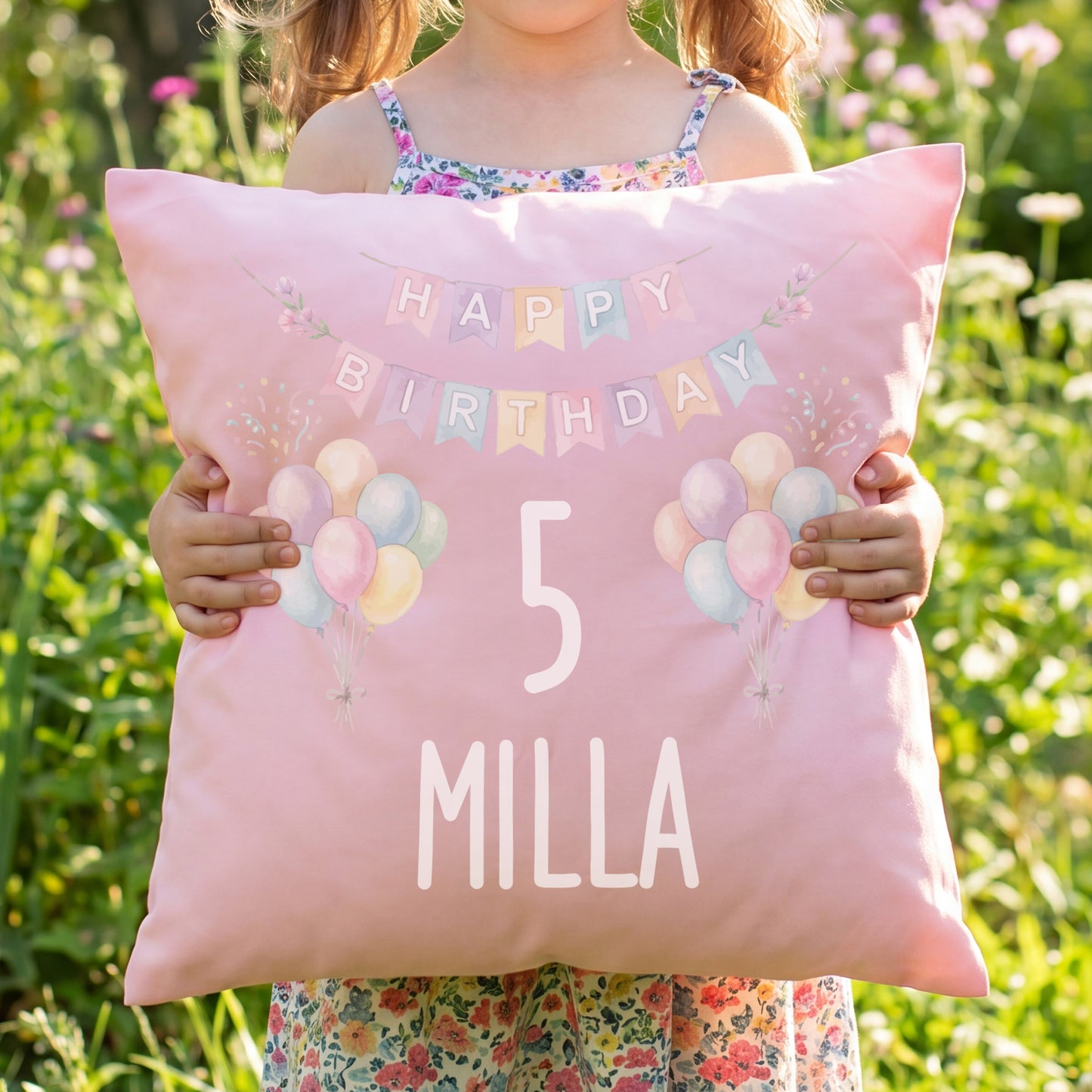 Mädchen hält rosa personalisiertes Geburtstagskissen mit Ballons, Zahl 5 und Name Milla
