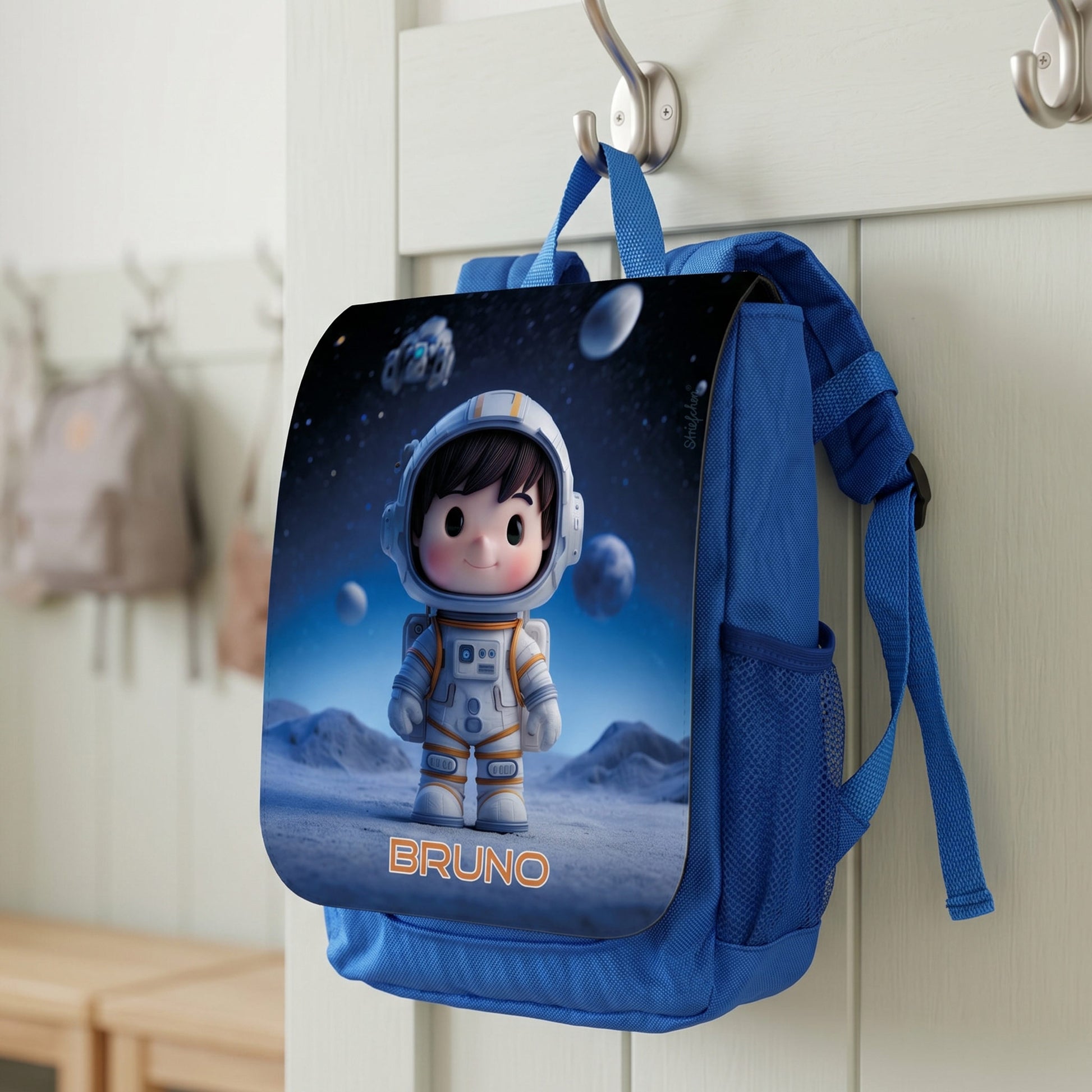 Blauer Kinderrucksack mit Astronaut-Motiv und Name Bruno an einer Garderobe