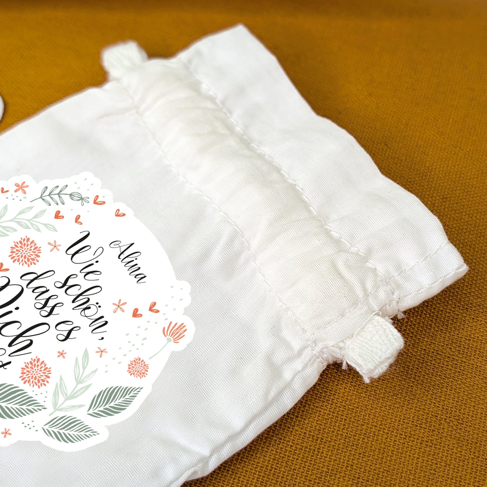 Nahaufnahme des Zugbands am bedruckten Geschenksäckchen mit Blumenmotiv
