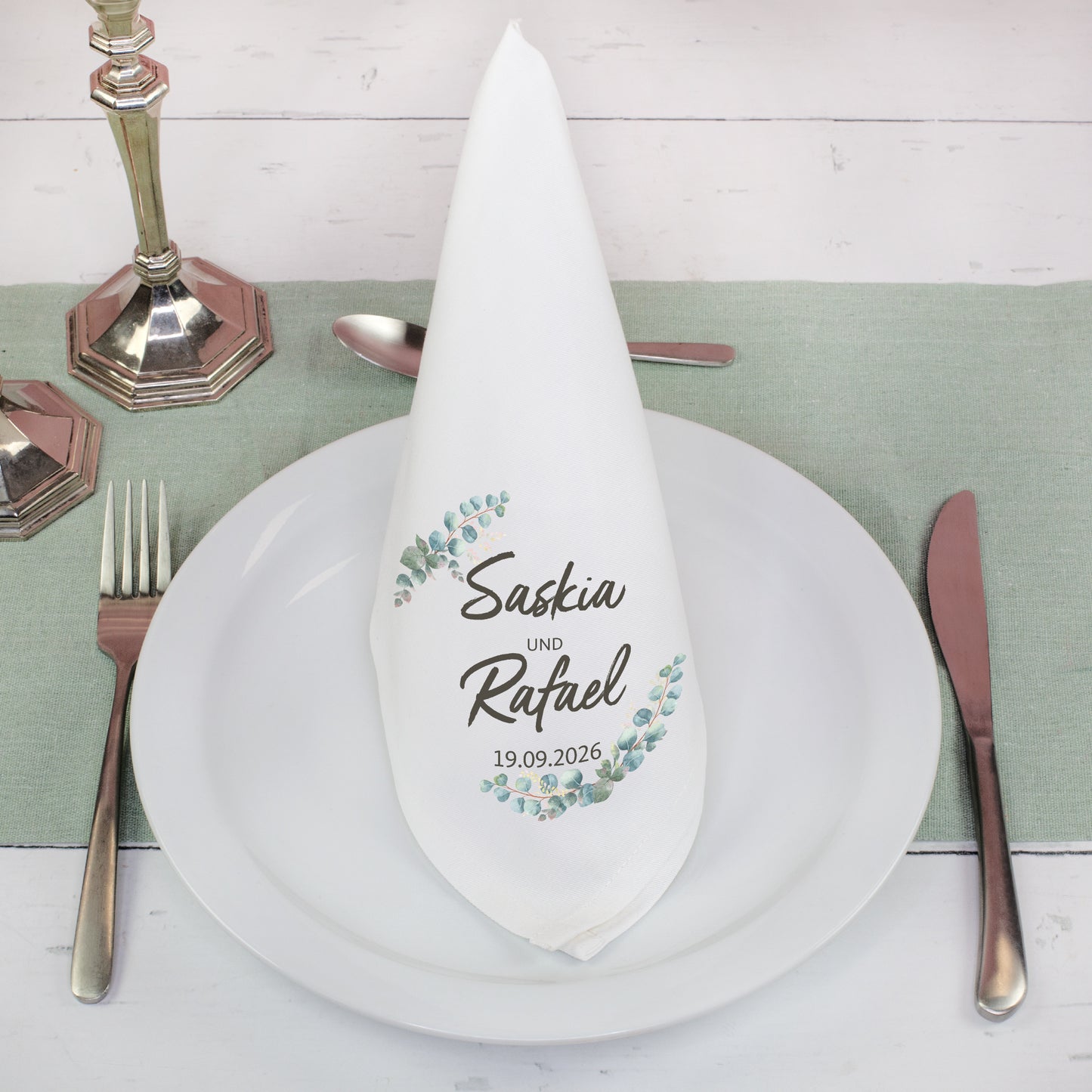 Personalisierte Stoffserviette mit Namen im Eukalyptus Design gefaltet auf gedecktem Hochzeitstisch