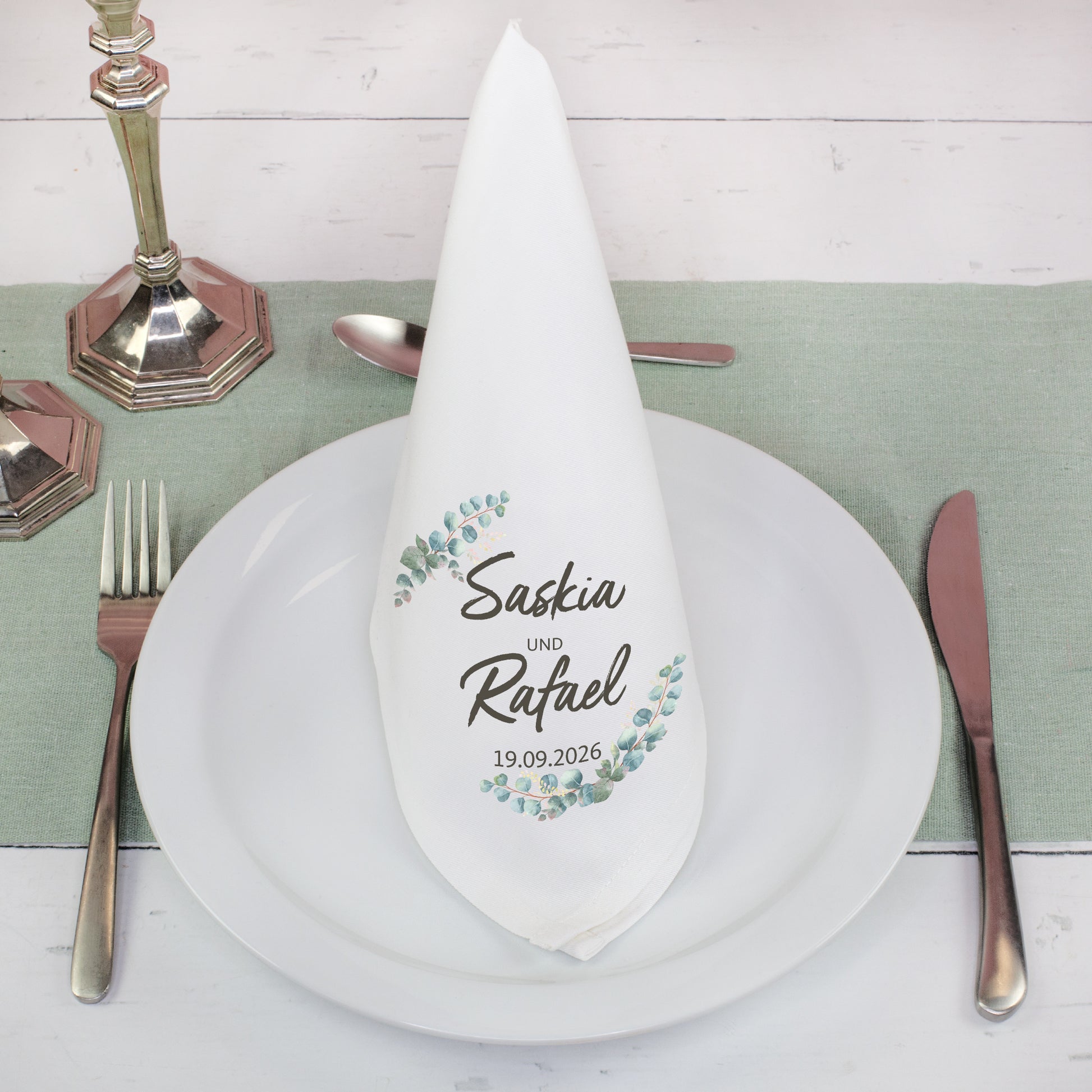 Personalisierte Stoffserviette mit Namen im Eukalyptus Design gefaltet auf gedecktem Hochzeitstisch