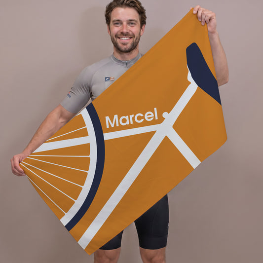Person hält großes Sporthandtuch mit Fahrradmotiv und personalisiertem Namen Marcel