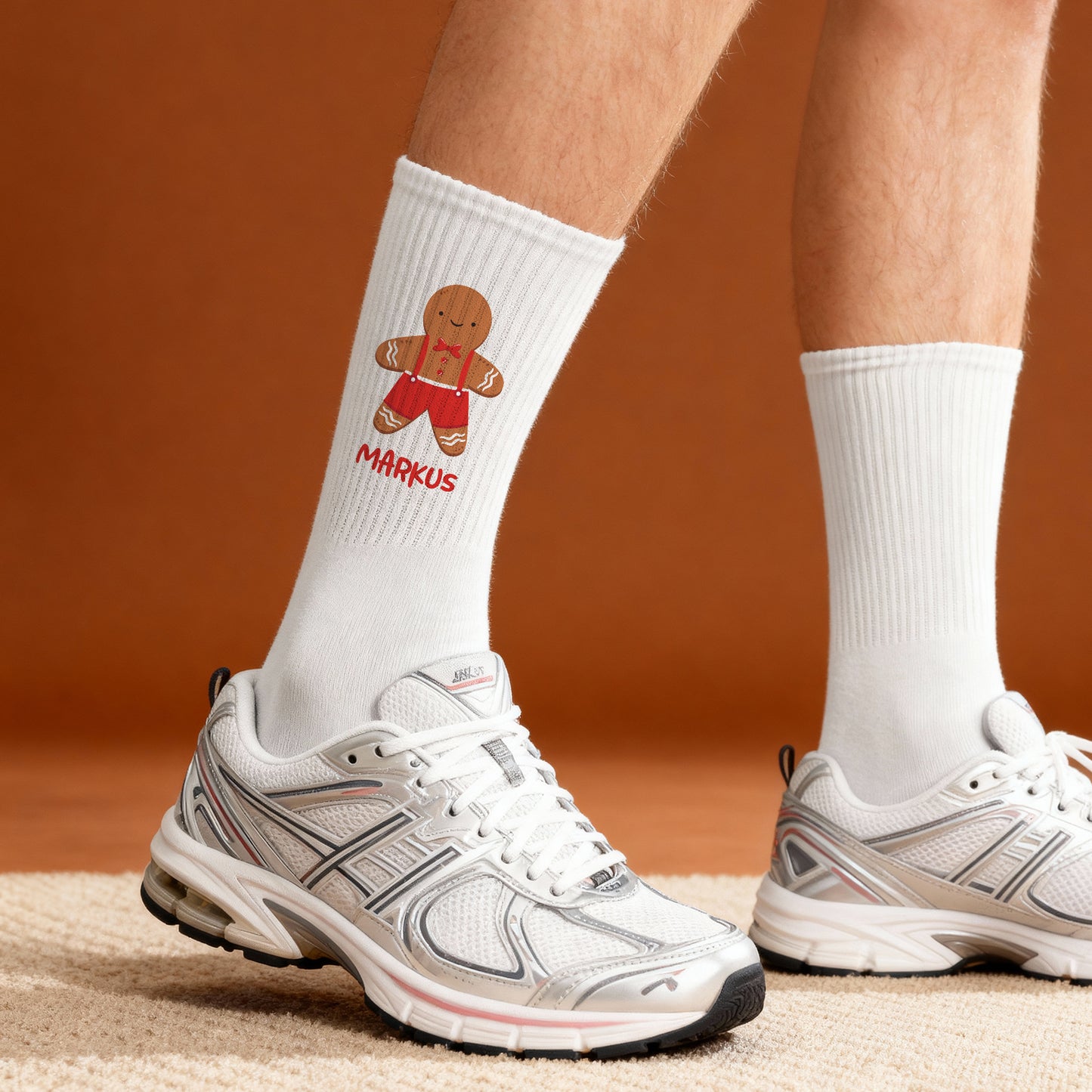 Weißer Tennissocken mit Lebkuchenmann-Motiv und personalisiertem Namen, getragen mit Sportschuh auf Teppichboden.