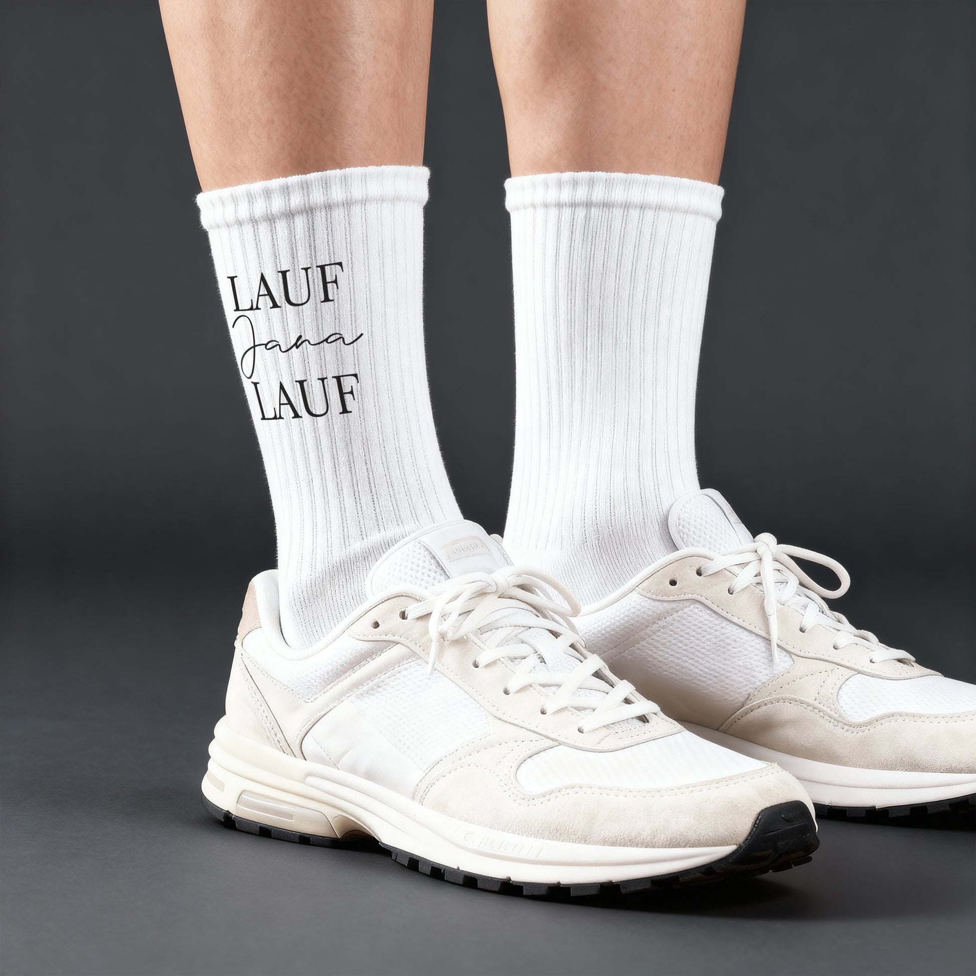 Person trägt weiße Sportsocken mit „Lauf Jana Lauf“-Aufdruck zu weißen Sneakern