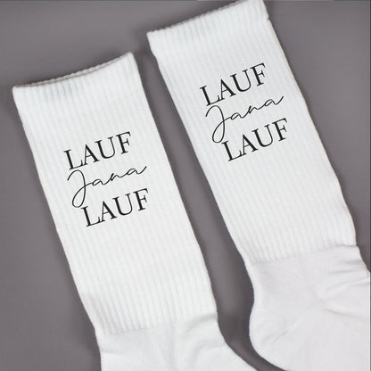 Nahaufnahme von weißen Socken mit „Lauf Jana Lauf“-Aufdruck und gerippter Struktur