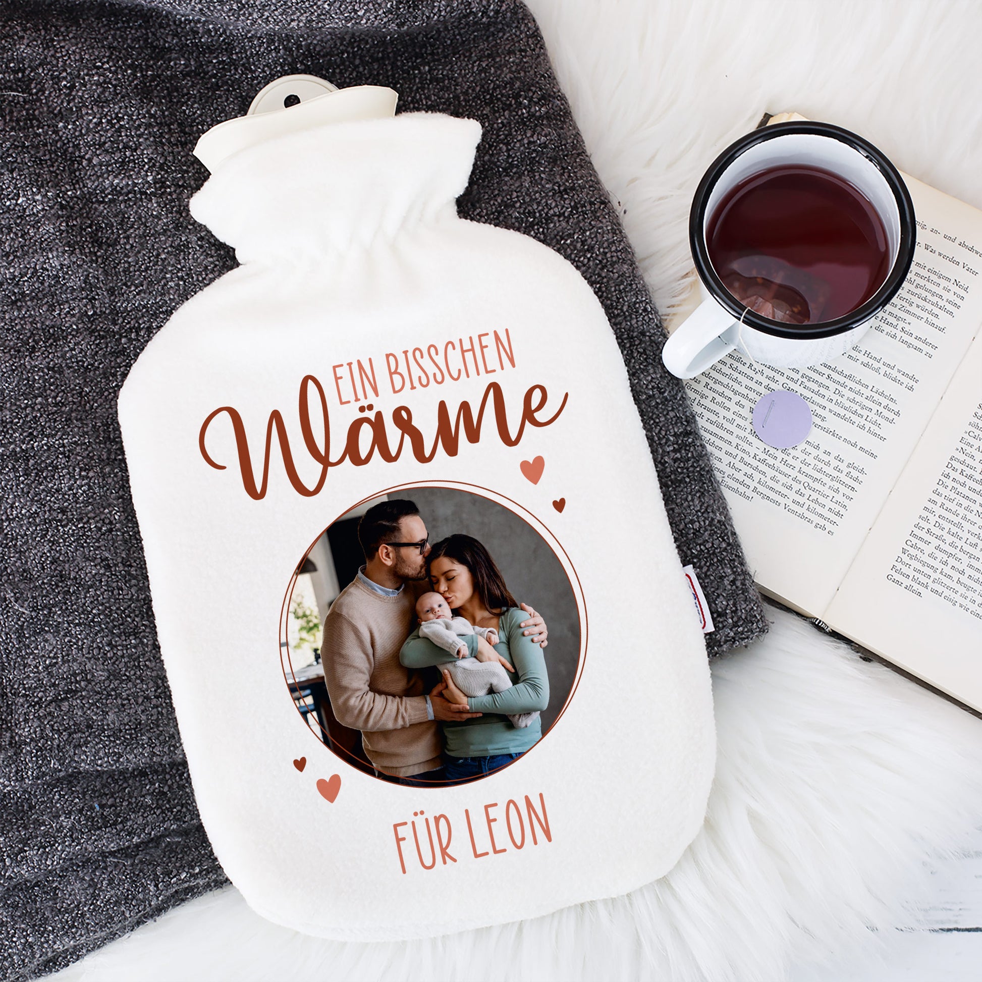 Personalisierte Wärmflasche mit bedrucktem Bezug mit Teetasse daneben.