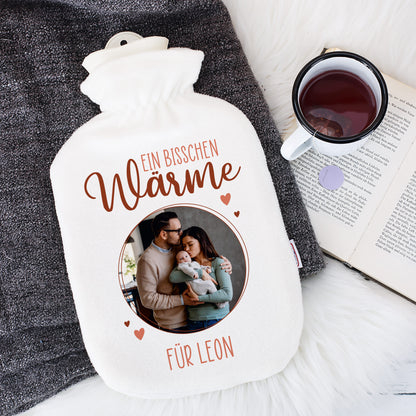 Personalisierte Wärmflasche mit bedrucktem Bezug mit Teetasse daneben.